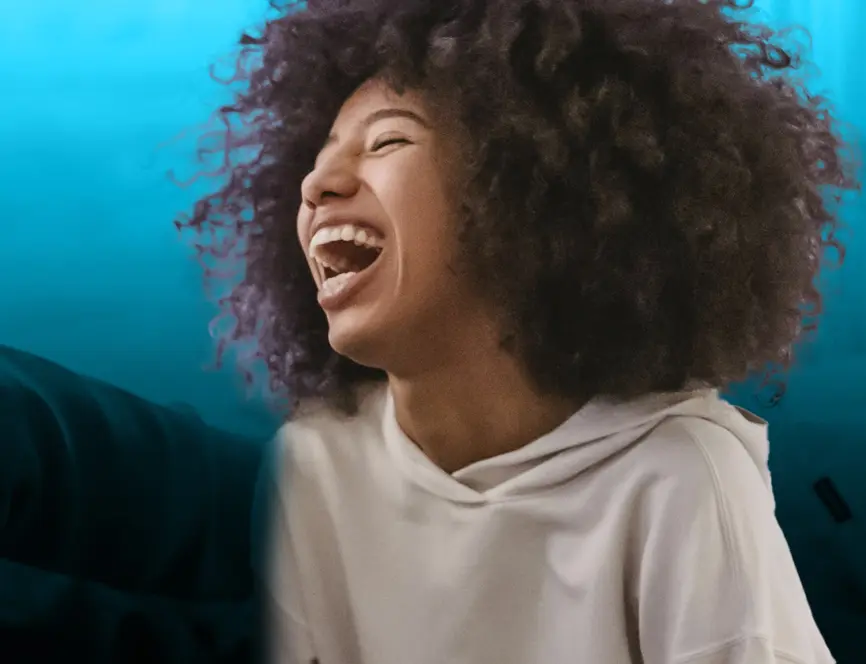Schwarze Frau mit Afro lacht herzlich