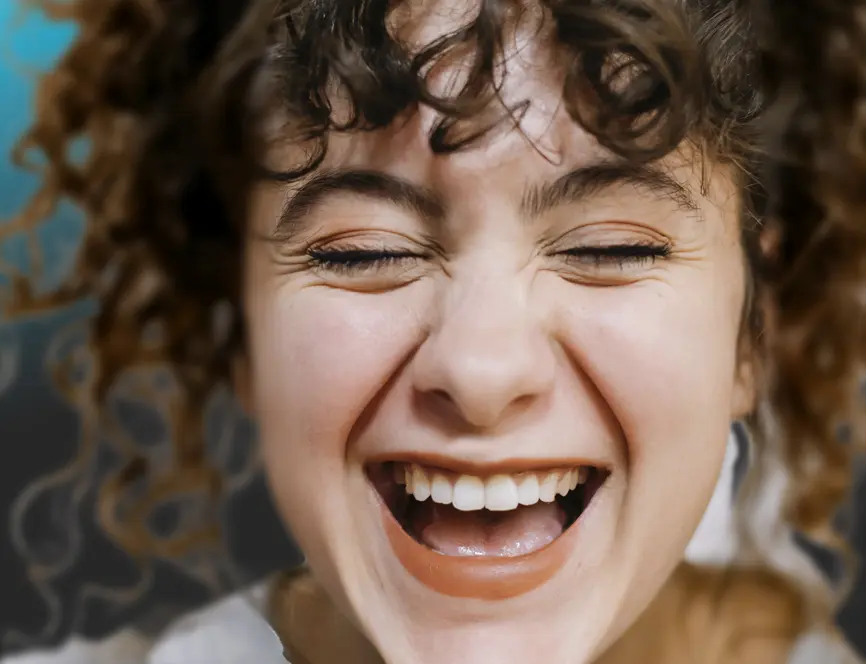 Frau mit Locken schüttet sich aus vor Lachen